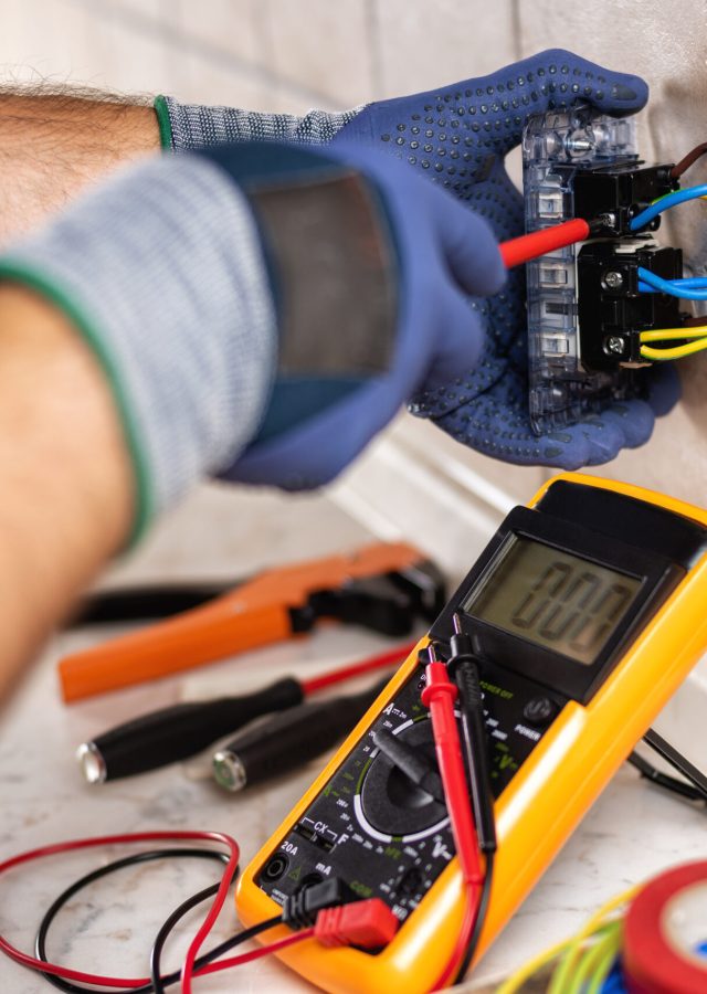 Electrician at work with screwdriver fixes the cable in the sockets of a residential electrical system. Construction industry.