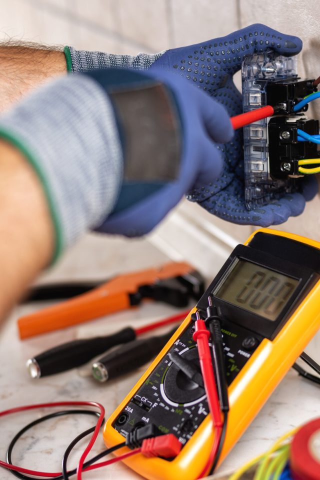 Electrician at work with screwdriver fixes the cable in the sockets of a residential electrical system. Construction industry.